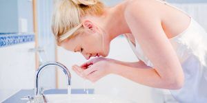 Woman washing her face at night to get ready to go to bed.