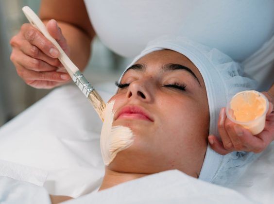 Christine Valmy student applying a skin care treatment mask to a client that is laying down.