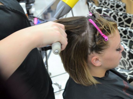 Woman sitting in a chair while having her hair blow-dried