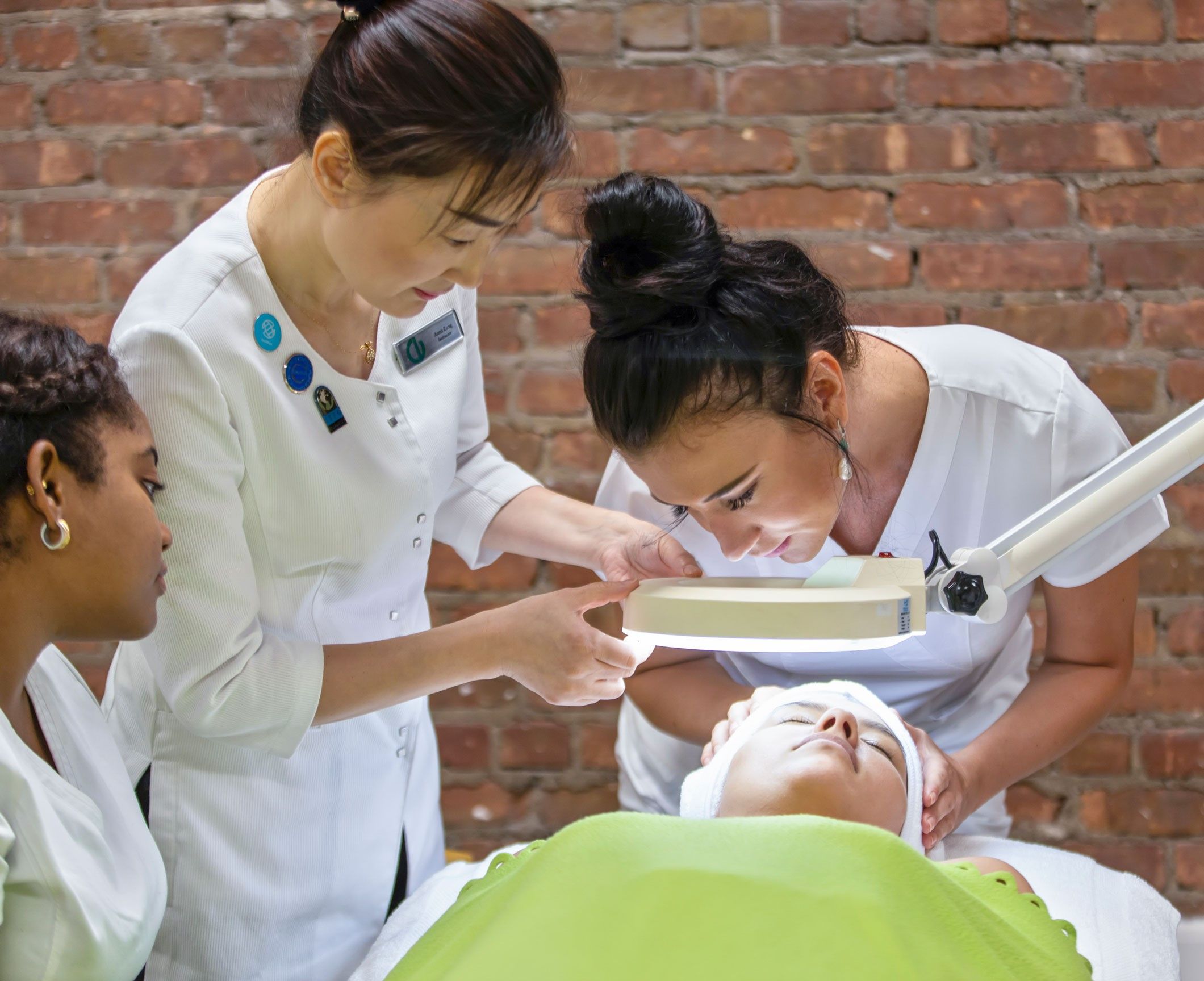 Christine Valmy esthetics instructor helping a student perform a skin analysis on another student.