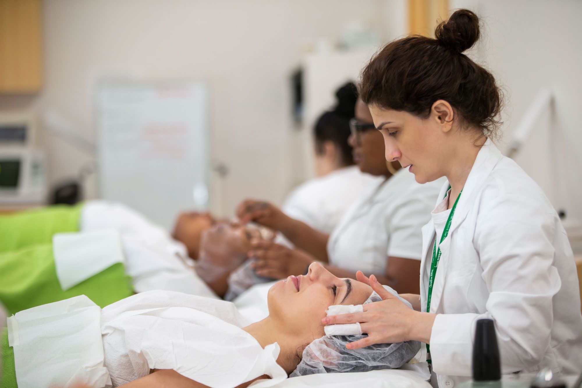 Row of Christine Valmy students practicing performing skin care treatments on each other. 