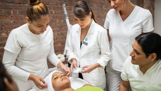 Christine Valmy student applying gold collagen mask with the help of an esthetics instructor