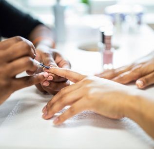 Christine Valmy Nail Specialty student practicing manicure techniques on another student.