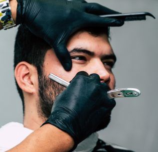 Barber shaving man's face with a straight razor