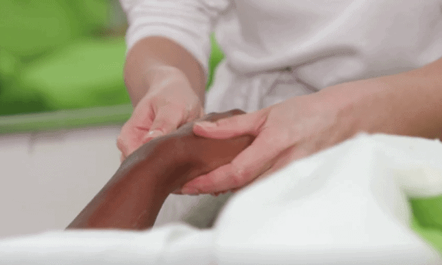 Esthetics student massaging a woman's hand