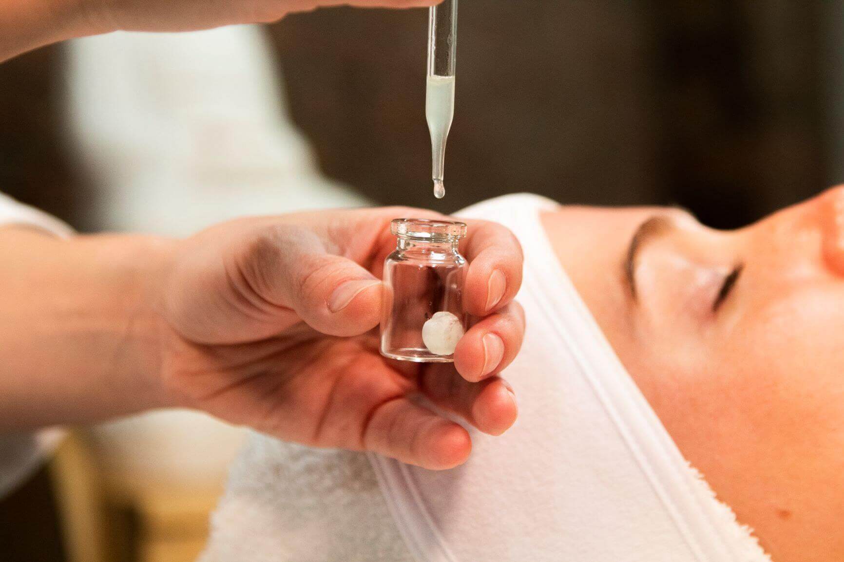 Hand dropping elixir into collagen vial to prepare treatment
